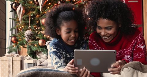 African mother and daughter spend holiday free time using tablet device choose gifts for family enjoy easy comfort remote shopping. E-commerce retail, Christmas sale, web store advertisement concept