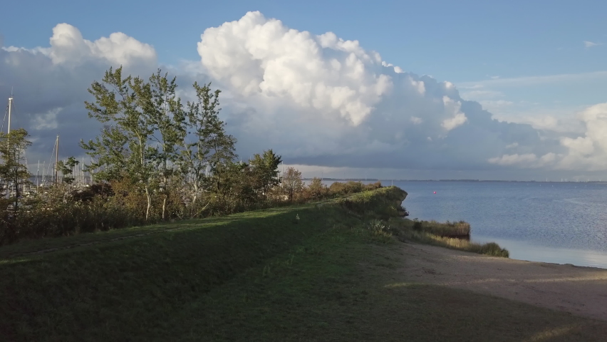 Drone flight at a sailboat port on the Grevelingen Sea in Zeeland. Evening sun with calm water, offshore wind gusts and great cloud formations. Bruinisse in the south of the Netherlands.