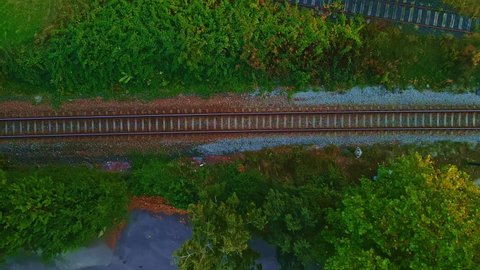 White passenger train passing by on railroad tracks with motion blur. Aerial top down view.