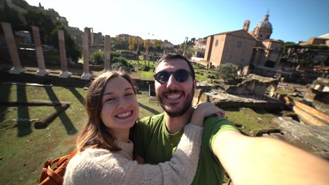 beautiful tourist couple smiling and taking selfie photo in the ruins of old city of Rome, Italy. Slow motion video