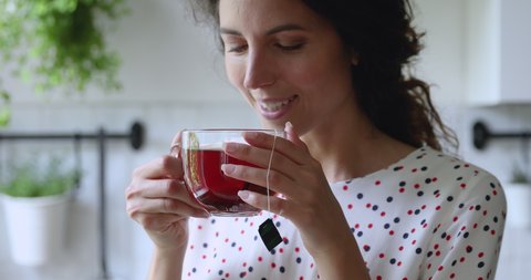 Woman holding mug with hot fresh brewed black teabag tea make sip smiles standing alone in kitchen close up view. Pleasant ritual, enjoy favorite drink while daydream in morning, start new day concept