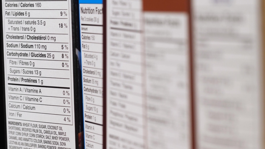 Focus pulling between multiple nutrition fact information lists on the side of food boxes. Royalty-Free Stock Footage #1061173582