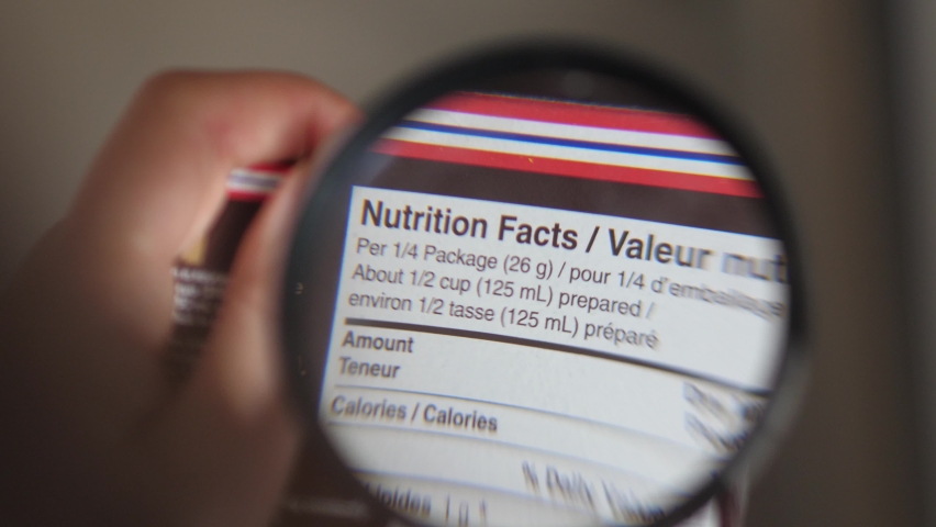 Holding a magnifying glass to look at the nutrition information facts on the side of a food product. Royalty-Free Stock Footage #1061173585