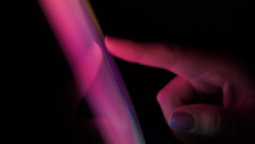 Young female checking on her phone during the night. Bright touchscreen in the dark. Browsing social networks. Procrastination before sleep. Vivid colored display with girl hand using her phone. | Shutterstock HD Video #1061176864