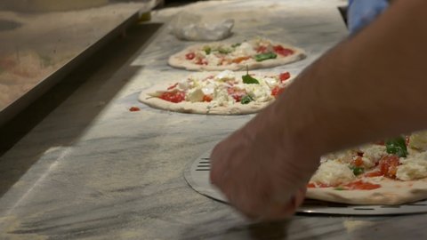 Preparing Pizza Margherita on a marble countertops. Pizzaiolo puts pizza dough on the peel. 