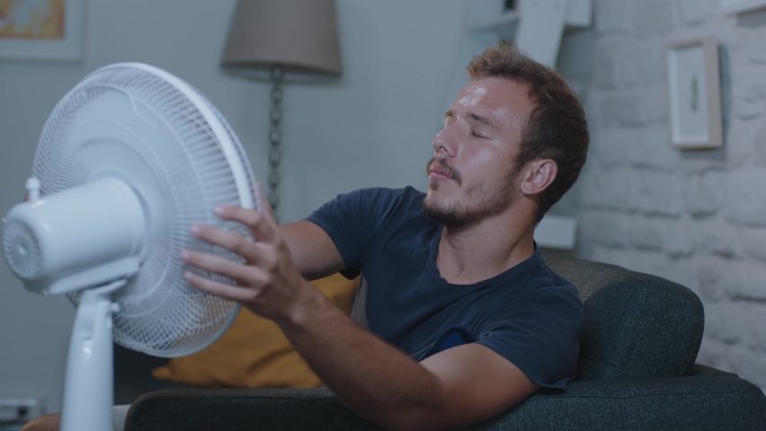 Man suffering from the summer heat and trying to cool off with her fan. A sweaty woman is disturbed by the air conditioner malfunction in the humidity concept. Royalty-Free Stock Footage #1061178448
