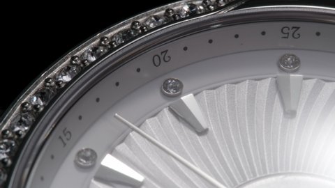 Upside down closeup view of rotating luxury swiss woman watch with shiny diamonds and running second arrow 