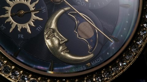 Extreme closeup view of luxury swiss women watch with blue nacre and diamonds. Second arrow passing by golden details and moon calendar while clock is slowly rotating 