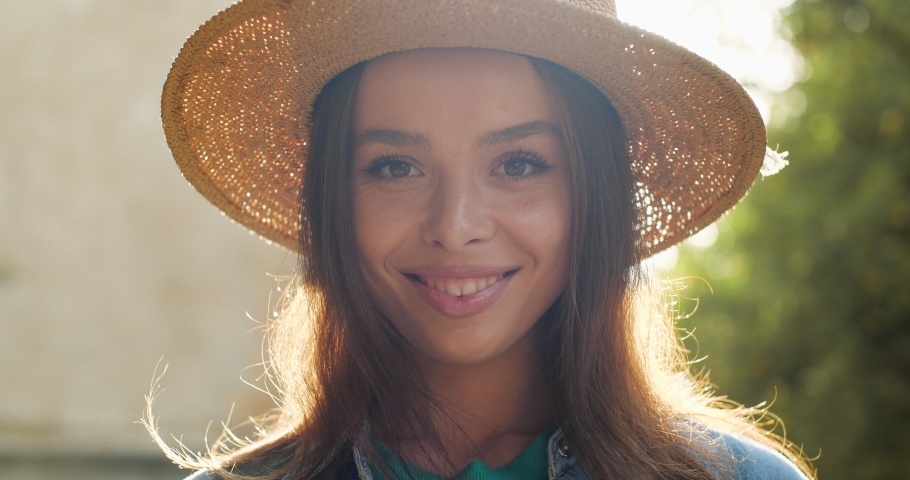  Portrait of Happy Girl in Straw Hat smiling at the Camera. Young Woman  posing on a sunny warmly Day, wearing trendy Hat, during walk in Park
