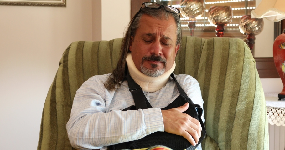 Painful sick man with neck and arm brace resting at home Royalty-Free Stock Footage #1061183416