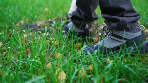 Nature travel tourist traveler man walking in boots on green grass. Closeup of feet legs on meadow. footsteps relax slow-mo