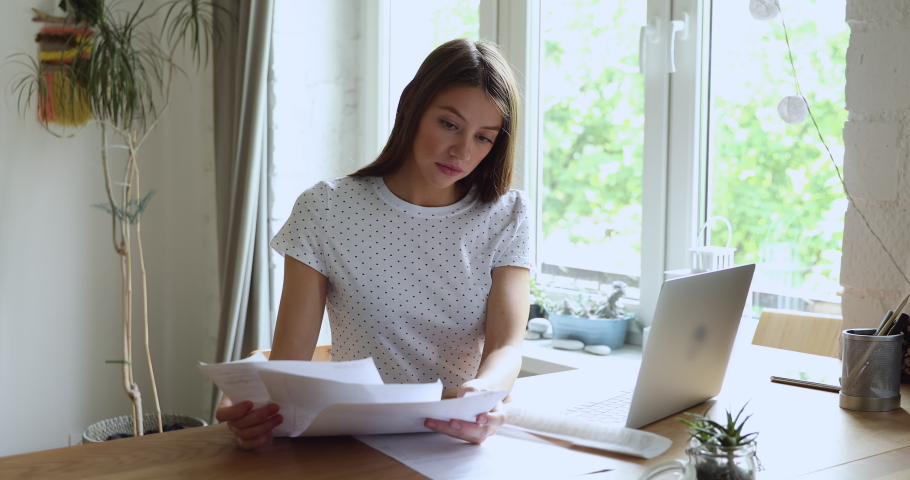 Smiling pleased young caucasian woman calculating domestic expenditures, managing household paper utility bills, planning monthly budget using computer application, feeling satisfied with enough money Royalty-Free Stock Footage #1061190607