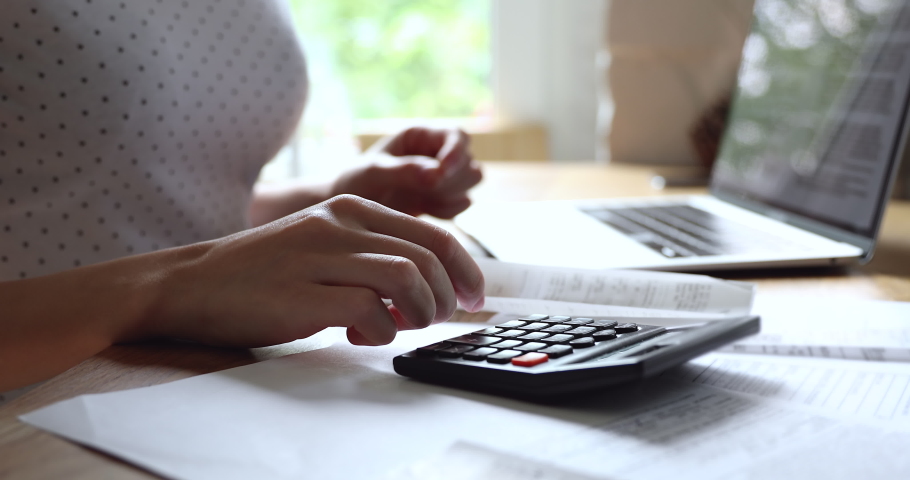 Close up young woman summarizing monthly incomes and outcomes with calculator, checking electronic bills in e-banking computer application, managing expenditures and household money payments. Royalty-Free Stock Footage #1061190646