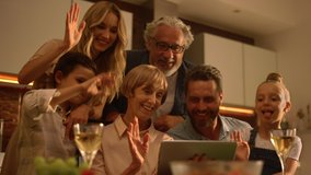 Cheerful family waving hands at camera during video call online. Positive people video chatting online on tablet with relatives. Smiling family using tablet computer together on kitchen - Powered by Shutterstock - Get 15% off with code: PIKWIZARD15