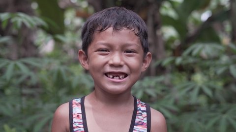 Close Up Slow Motion Video Portrait of a Handsome Cute Toothless Asian Filipino Kid Smiling into the Camera from the Rural Village in the Philippines with Extreme Happiness