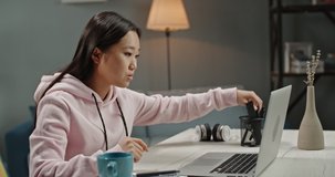 Young asian girl remotely working from home. Positive woman having a video conference on her laptop, talking and smiling 4k footage