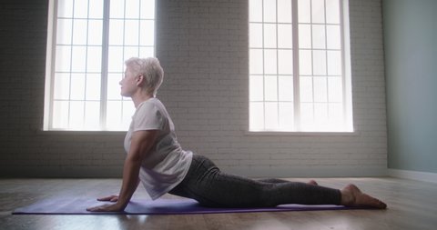 Senior fit caucasian woman doing pilates. Mature athlete exercising and stretching, doing yoga, keeping a healthy lifestyle - wellness 4k footage