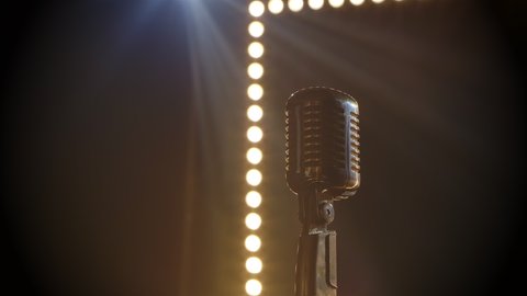 Microphone on stage with smoke anding light behind it. Professional concert vintage glare microphone for record or speak to audience on stage in empty retro club close up.