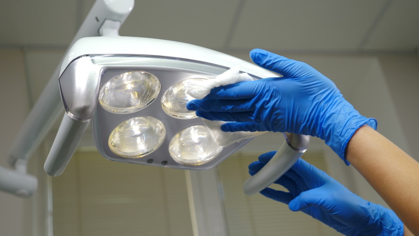 Cleaning medical lamp in dental clinic, operating medical facility in cabinet. Clinic Hygiene Concept. Sterilization and disinfection, Preparing dental cabinet office before treating patient. 4 k | Shutterstock HD Video #1061201635