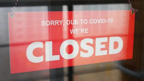 A business owner changes the sign on the front door with the inscription OPEN to the CLOSED due to COVID-19 close-up