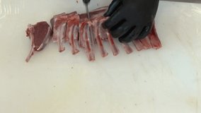 Butcher using knife cutting pieces of Making cutlets from lamb ribs. Deboning of Lamb meat. Video