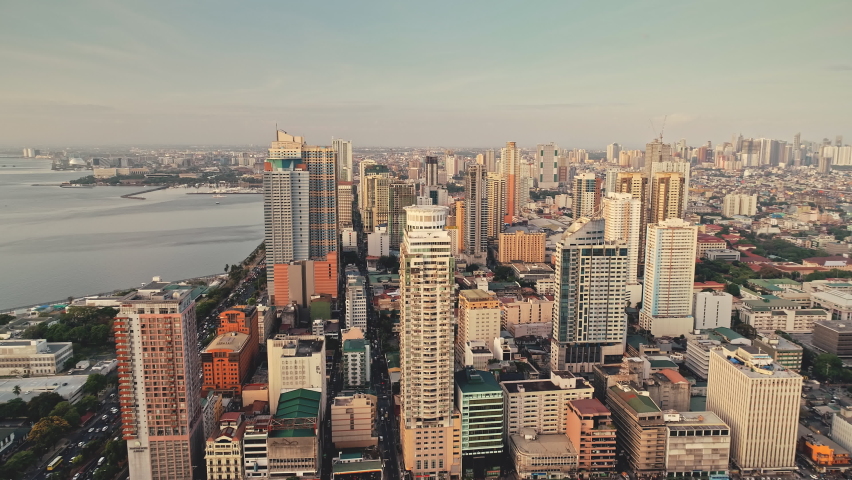 Tropic city with modern buildings and skyscrapers aerial. Philippines metropolis town of Manila at ocean coast. Beautiful streets and roads. Cinematic cityscape scenery at summer sunny day