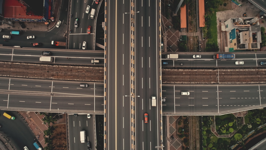 Top down cross traffic highway with cars, trucks aerial. Urban transportation at bridge road at metropolis city of Manila, Philippines, Asia. Cinematic cityscape of downtown freeway drone shot