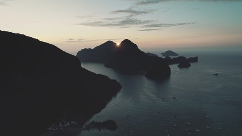 Aerial sunrise over mountain island silhouette at sea bay. Nobody nature seascape at serene ocean harbor at sun rise light. Majestic tropic paradise islets at cinematic soft sunlight scenery