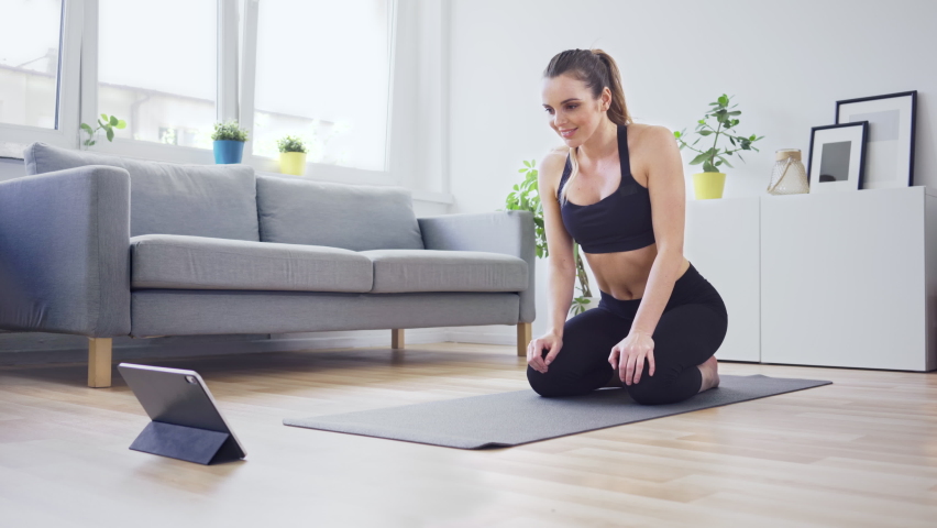 Concentrated woman doing planks while watching online workout on digital tablet Royalty-Free Stock Footage #1061209255