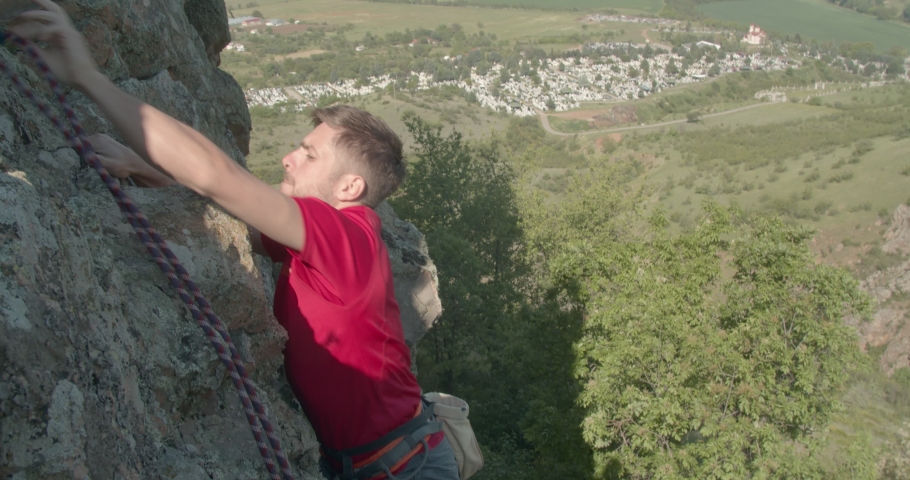 Young man climbing the rocks on a sunny day