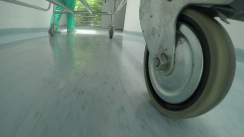 Low level close up of medical professional bed wheel moving on hallway 