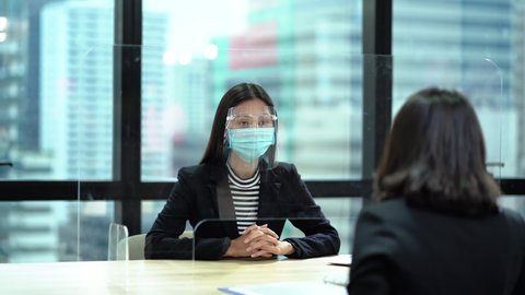 asian businesswoman wearing protective medical face mask and face shield Job. Interview Job through the partition in office prevents covid - 19 or coronavirus  pandemic new normal social distancing.