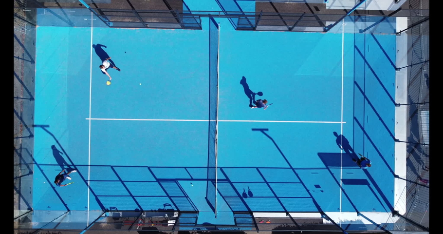 Four players swinging balls on a padel court in Cologne, Germany | Shutterstock HD Video #1061217532