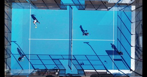 Four players swinging balls on a padel court in Cologne, Germany
