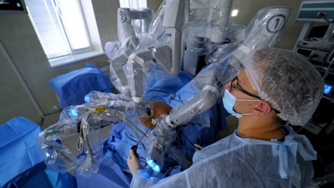 Surgery with robotic equipment. Doctor near the surgical robot during the minimally invasive operation in modern hospital. Top view.