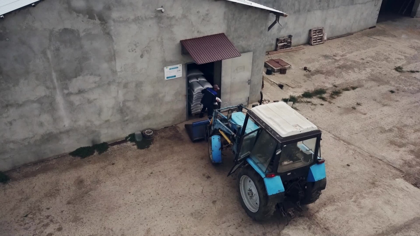 the man gets out of the tractor. loading bags of grain from the tractor bucket