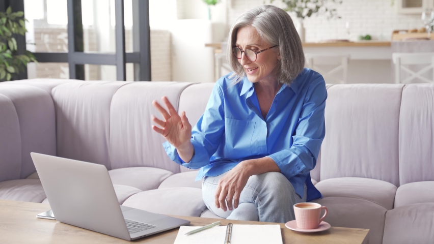 Happy old senior woman grandmother video conference calling talking enjoying social distance party, virtual family online chat meeting with grandchildren or friends using laptop computer at home. | Shutterstock HD Video #1061230507