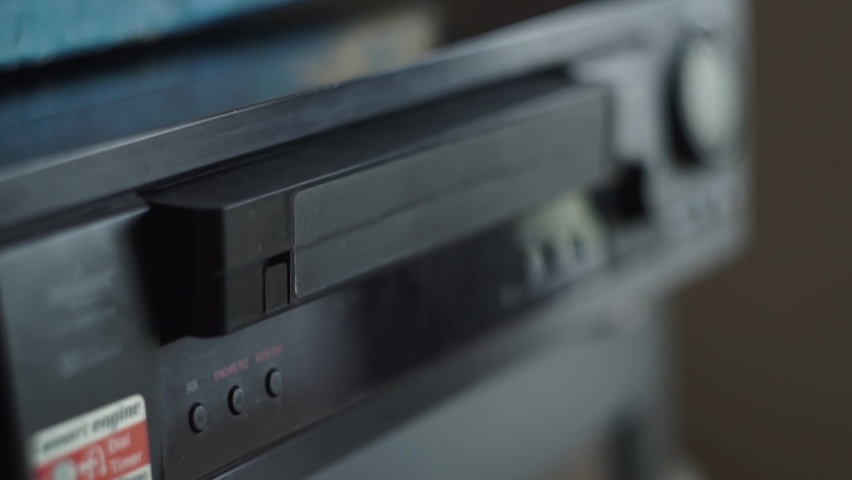 Hand, fingers insert a video cassette into an old, dirty VCR. Shallow depth of field, bokeh. Day, room Royalty-Free Stock Footage #1061231527