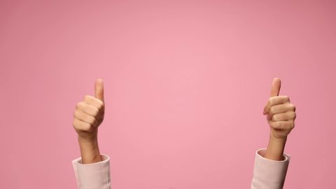 woman's hands making rock and roll gesture, pointing fingers and celebrating, making thumbs up sign and dancing on pink background
