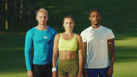 Group portrait of nice-looking healthy people in sports outdoors. Caucasian and afro-american athletes fitness guru posing for camera with crossed arms.