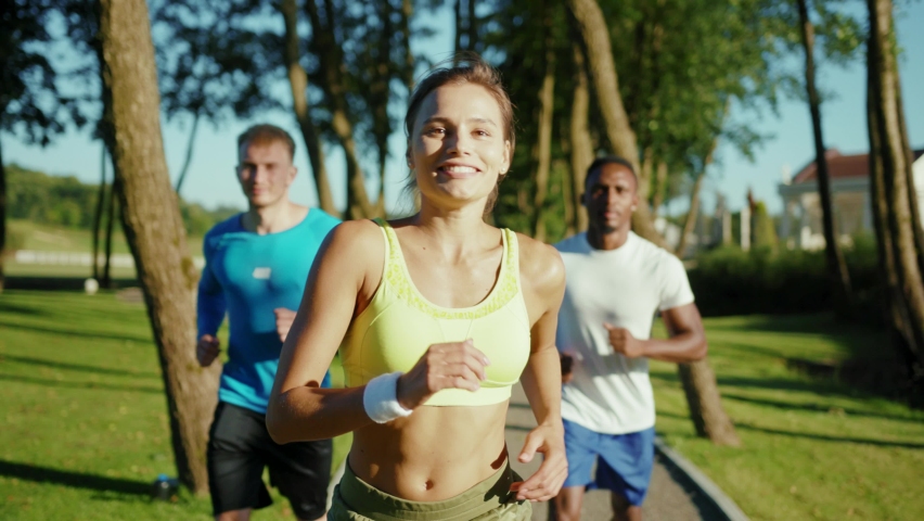 Beautiful active fitness trip jogging in wonderful park on sunny morning. Three friendly young multi-ethnic people doing healthy sports activity training workout outdoors. | Shutterstock HD Video #1061233291