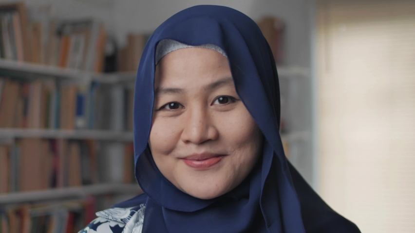 Happy Asian muslim woman wearing hijab smiling to camera, female student in library, close up Royalty-Free Stock Footage #1061233708