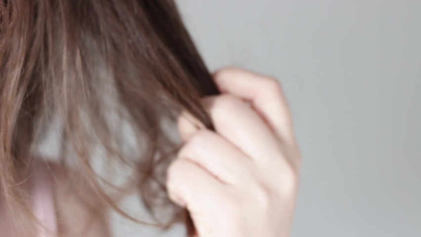 Girl holds a strand of hair front view, hair loss concept | Shutterstock HD Video #1061235775