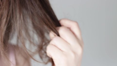 Girl holds a strand of hair front view, hair loss concept