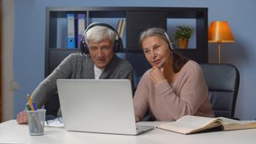 Senior couple woman studying at home getting online courses. Portrait of aged man and woman in headphones having video call and chatting with family on laptop