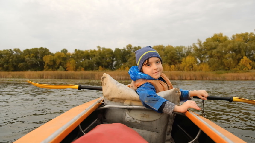 Evening kayak trip along the river in autumn. The active lifestyle of the child in the family.
