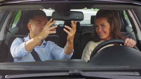 driver courses and people concept - woman and driving school instructor adjusting mirror in car