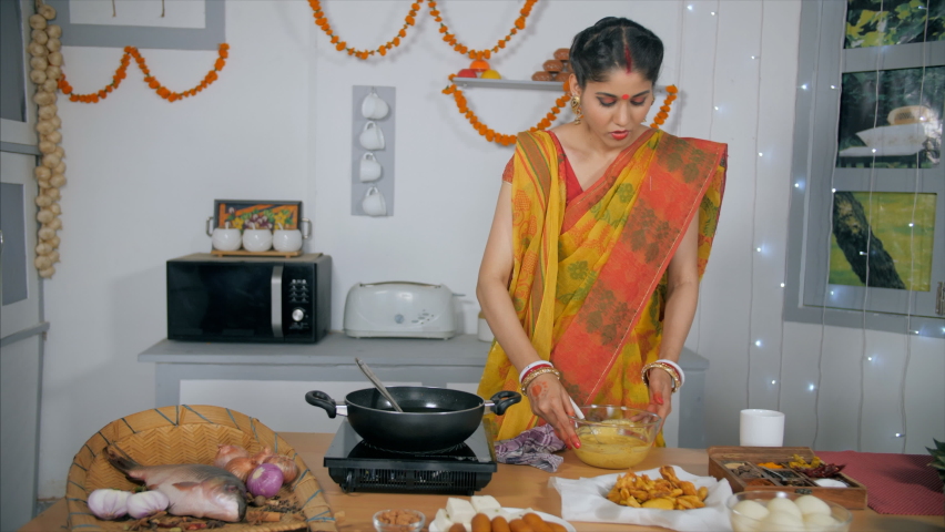A caring Bengali housewife cleaning the kitchen counter properly after cooking. Medium shot of an Indian female in traditional saree in her kitchen - Festival food preparation