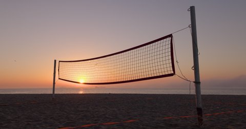 Volleyball net and ocean beach at sunrise