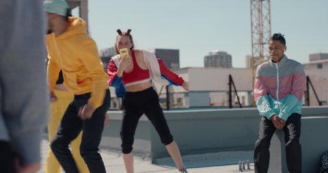 man breakdancing on rooftop at hip hop dance party performing crazy breakdance moves with friends dancing and celebrating